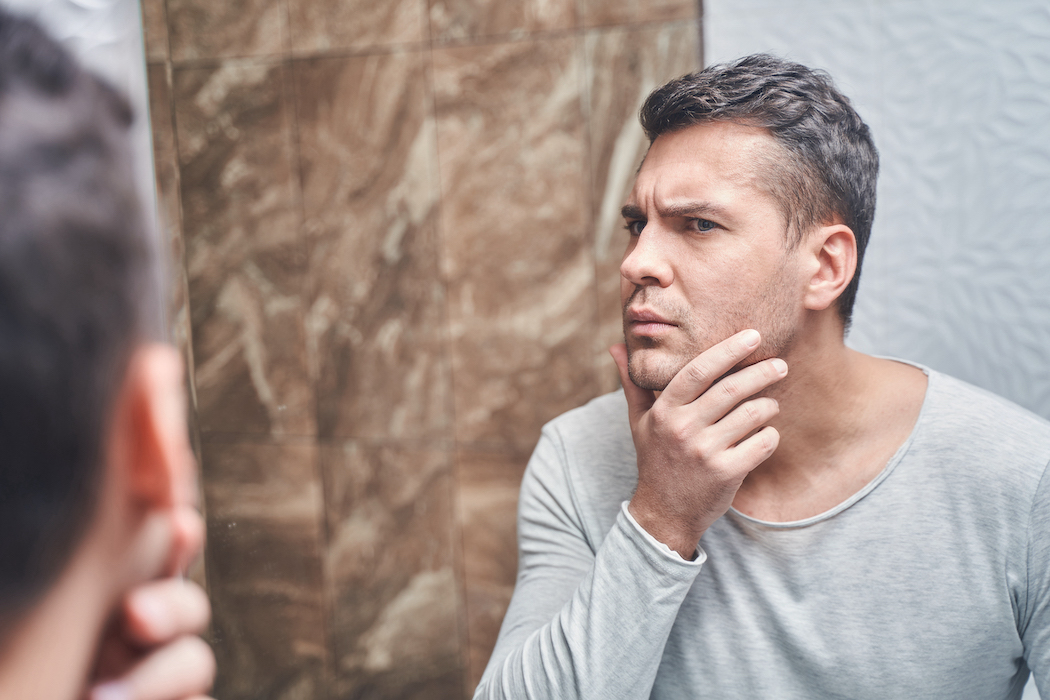Man examining his face in mirror